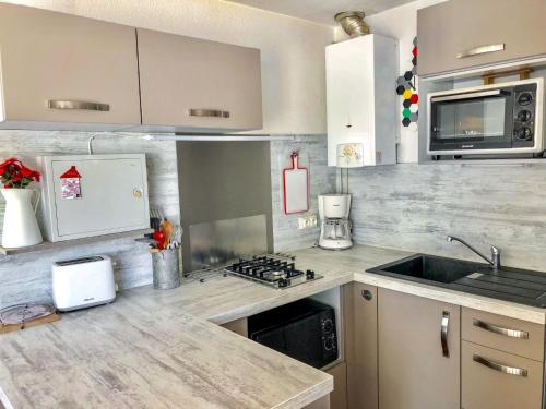une cuisine avec un évier et une cuisinière four supérieur dans l'établissement Apartment Les Agathes Plus by Interhome, au Cap d'Agde