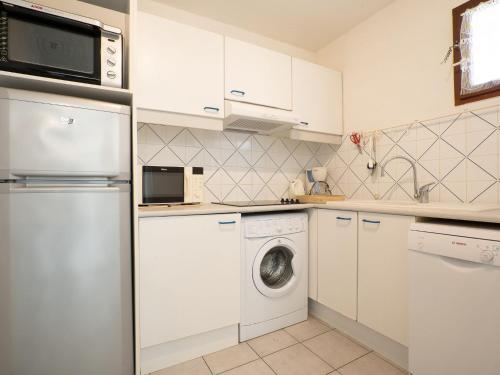 une cuisine avec des armoires blanches et une laveuse et une sécheuse dans l'établissement Apartment Le Sunset-Cap Sud-7 by Interhome, au Cap d'Agde