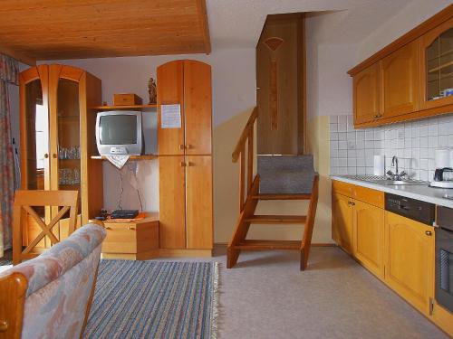 Il comprend une cuisine avec des placards en bois, une télévision et un canapé. dans l'établissement Apartment Untererhof-1 by Interhome, à Pankrazberg