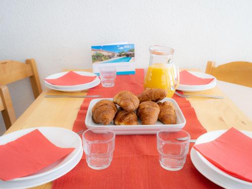 une table avec une plaque de beignets et de jus d'orange dans l'établissement Apartment Le Borsat - Val Claret-10 by Interhome, à Tignes