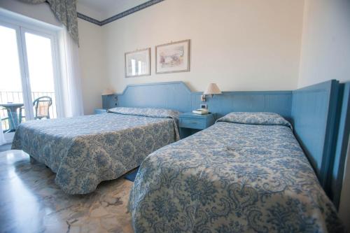 a hotel room with two beds and a window at Hotel Ariston in Imperia