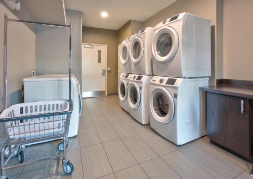a laundry room with three washing machines and a cart at Staybridge Suites Plano - Richardson Area by IHG in Plano