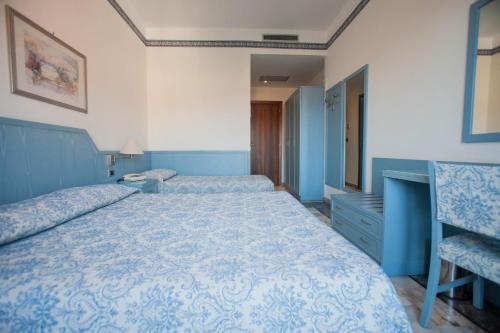 a bedroom with a large bed with a blue comforter at Hotel Ariston in Imperia