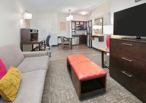 a living room with a couch and a flat screen tv at Staybridge Suites Plano - Richardson Area by IHG in Plano