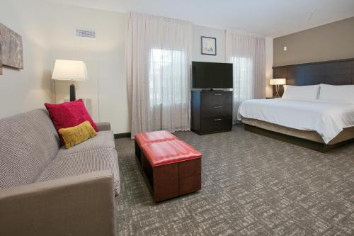 a hotel room with a bed and a couch and a tv at Staybridge Suites Plano - Richardson Area by IHG in Plano