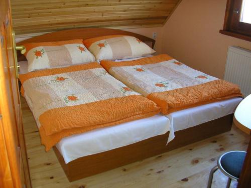 a bedroom with two beds with orange and white blankets at Mária Kičáková TATRY MKS in Štrba