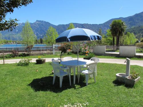 einem Tisch mit zwei Stühlen und einem Regenschirm im Gras in der Unterkunft Apartment Martinelli by Interhome in Calceranica al Lago