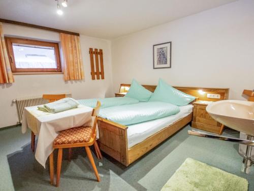 Schlafzimmer mit einem Bett, einem Tisch und einem Waschbecken in der Unterkunft Apartment Christian by Interhome in Pettneu am Arlberg