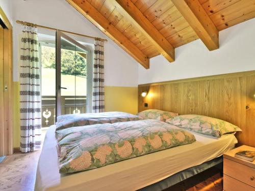 a bedroom with two beds and a large window at Apartment Cecilia-4 by Interhome in Campitello
