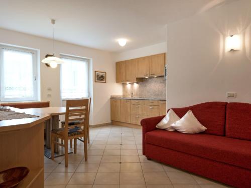 Il comprend un salon avec un canapé rouge et une cuisine. dans l'établissement Apartment Ornella-1 by Interhome, à Santa Cristina Valgardena