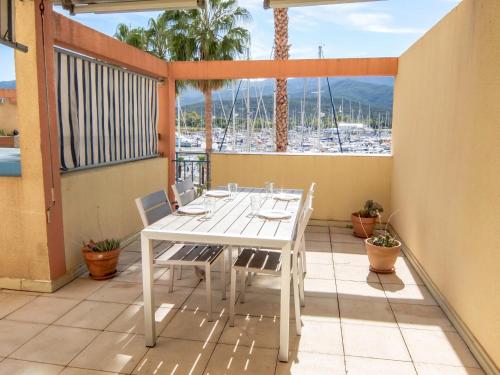 a white table and chairs on a balcony with palm trees at Apartment Santa Maria by Interhome in Plage dʼArgelès