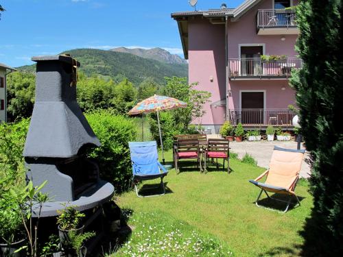 eine Gruppe Stühle und ein Regenschirm auf einem Hof in der Unterkunft Apartment Deval-2 by Interhome in Calceranica al Lago