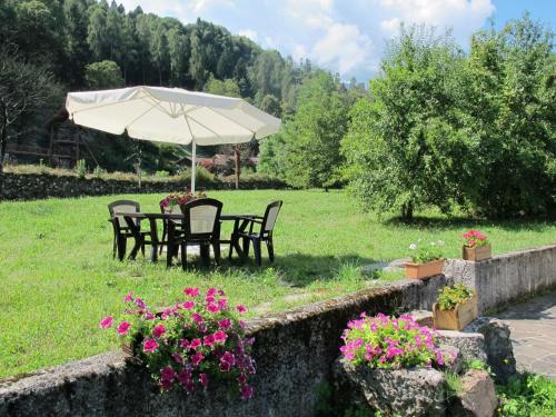 uma mesa e cadeiras sob um guarda-sol num campo em Holiday Home Casa al Mulino by Interhome em Calceranica al Lago