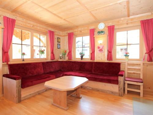 ein Wohnzimmer mit einem roten Sofa und einem Tisch in der Unterkunft Holiday Home Schwendau-1 by Interhome in Hippach