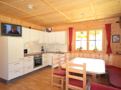 a kitchen with white cabinets and a table with chairs at Holiday Home Schwendau-1 by Interhome in Hippach