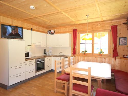 a kitchen with white cabinets and a table with chairs at Holiday Home Schwendau-2 by Interhome in Hippach