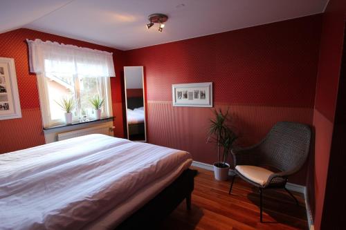 a bedroom with red walls and a bed and a chair at At Home Bed & Breakfast in Gothenburg