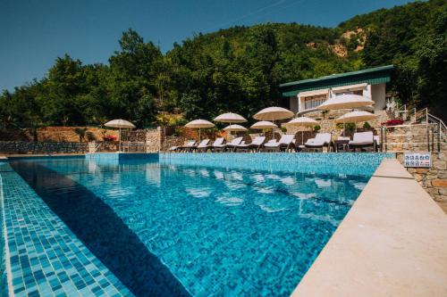 a swimming pool with chairs and umbrellas on a resort at Vila Bisera in Ohrid