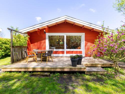a red cabin with a table and chairs on a deck at Holiday Home Rusthoeve 14 by Interhome in Sint Maartensvlotbrug