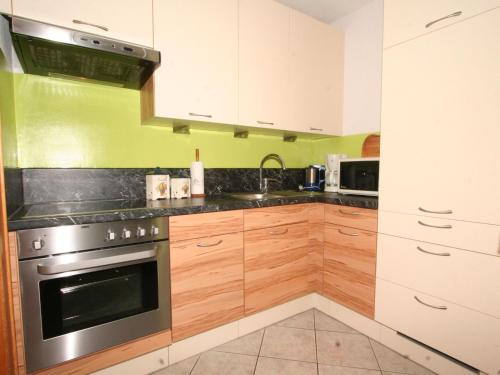 eine Küche mit Holzschränken und einem Edelstahlofen in der Unterkunft Apartment Evi by Interhome in Fliess