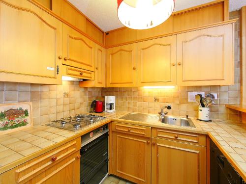 a kitchen with wooden cabinets and a sink at Apartment Sapin Bleu 6 by Interhome in Villars-sur-Ollon