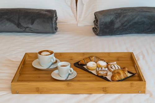 a tray with two cups of coffee and pastries on a bed at Lake Front Hotel Mirage in Riva del Garda