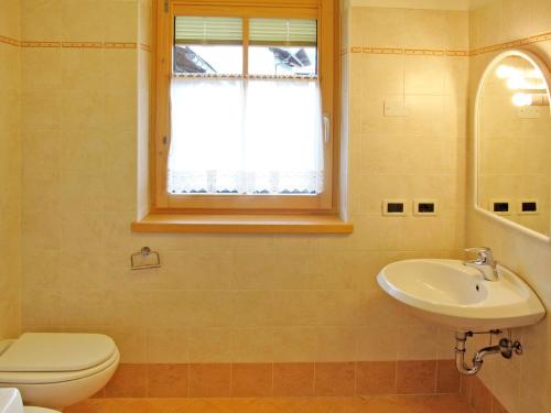 a bathroom with a toilet and a sink and a window at Apartment Giovanni - CPO359 by Interhome in Campitello