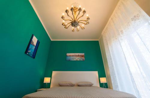 una camera verde con un letto e un lampadario a braccio di B&B Trapani In a Trapani