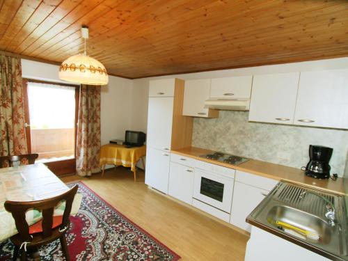 cocina con armarios blancos, mesa y comedor en Apartment Jägerhof-2 by Interhome, en Hochpillberg