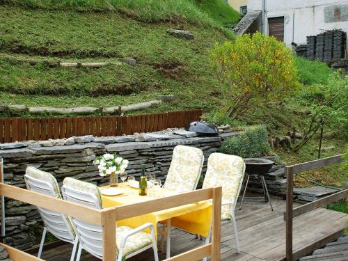 a table and chairs on a patio with a stone wall at Apartment Casa Strecce 1 by Interhome in Crana