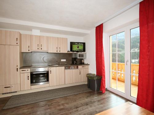 a kitchen with wooden cabinets and a red curtain at Apartment Pfeifer-2 by Interhome in Pians