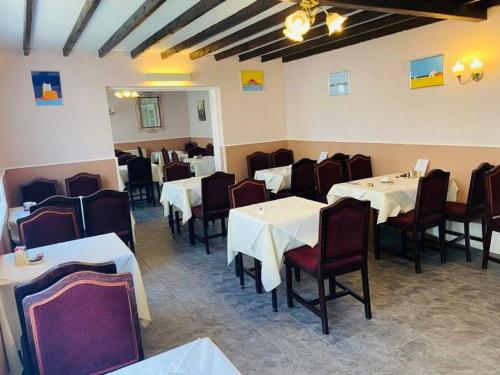 uma sala de jantar com mesas brancas e cadeiras vermelhas em Seawold Guest House em St Brelade