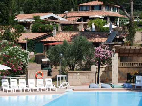 einen Pool mit weißen Stühlen und ein Haus in der Unterkunft Holiday Home Il Borgo-1 by Interhome in Casale Marittimo