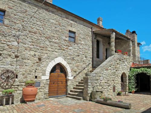 um antigo edifício de pedra com uma porta de madeira e escadas em Apartment Rosa - Borgo la Civitella by Interhome em Roccastrada
