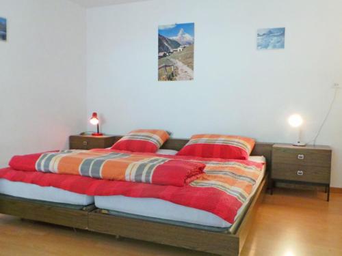ein Bett mit zwei roten Kissen in einem Zimmer in der Unterkunft Apartment Sonnheim by Interhome in Zermatt