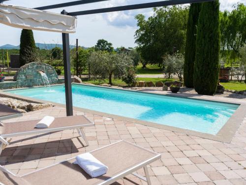 a swimming pool with a chair and an umbrella at Villa Cipresso by Interhome in Sutri
