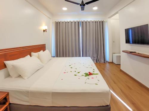 a bedroom with a large white bed with flowers on it at Dhonkamana Stay in Thoddoo