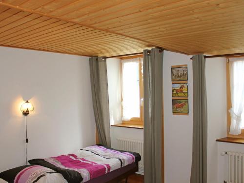 a bed in a room with a wooden ceiling at Apartment Les Grangettes by Interhome in Auberson