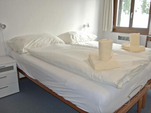 a bed with white sheets and two towels on it at Apartment Residenza Chesa Margun 46-3 by Interhome in Surlej