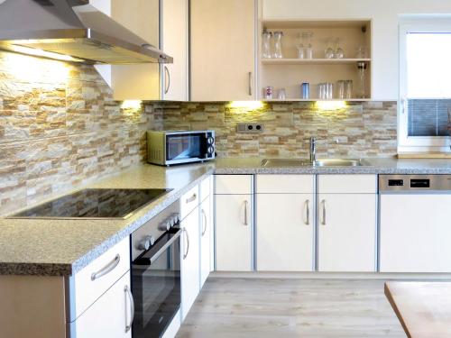 a kitchen with white cabinets and a sink and a microwave at Apartment Hannah Lena by Interhome in Wiesing