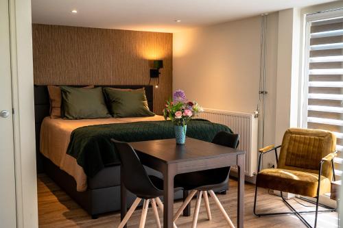 Un dormitorio con una cama y una mesa con flores. en B&B de Scherpenhof, en Leur