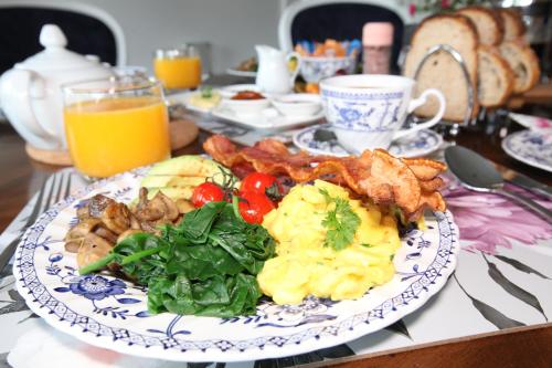 a plate of food with eggs bacon and greens on a table at Explorers Lodge in New Norfolk