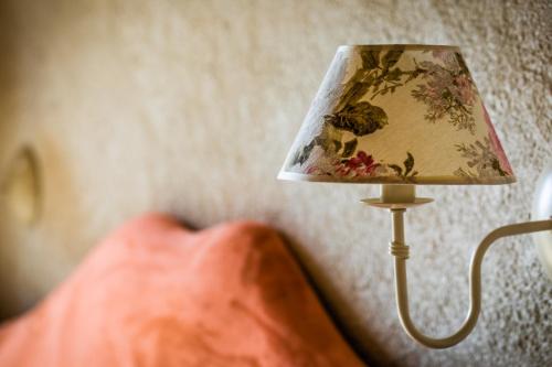 a lamp with a flowery lampshade next to a bed at Willa u Steni in Gliczarów
