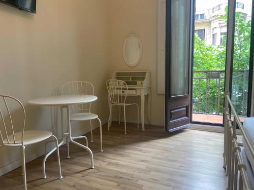 Habitación con 2 mesas, sillas y ventana en Lumine Luxury Suites by gaiarooms, en Barcelona