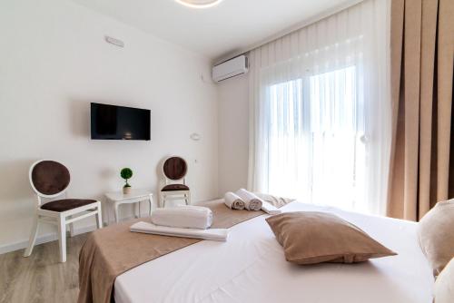 a white bedroom with a bed and a window at Apartments Hoxha in Ulcinj