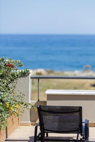 a black chair sitting on a balcony looking at the ocean at Adele Riva in Adelianos Kampos