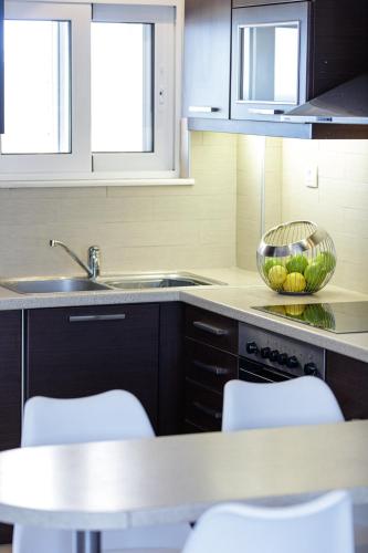 a kitchen with a sink and a counter with chairs at Adele Riva in Adelianos Kampos