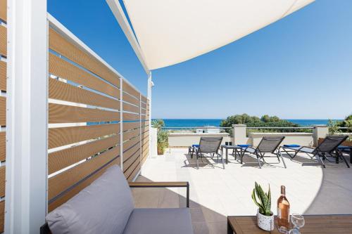 a patio with a couch and chairs and the ocean at Adele Riva in Adelianos Kampos
