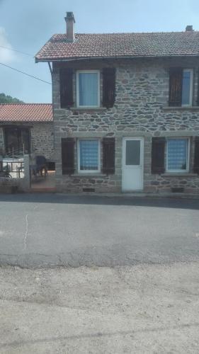 a stone house with a white door and a patio at Git'a'Gnac in Retournac
