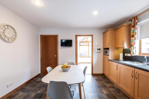 a kitchen with a table and chairs and a clock on the wall at Bowmore in Lossiemouth